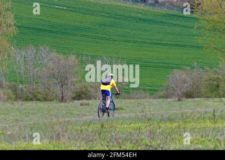 Cycliste masculin en chemise jaune et short bleu en vitesse Descente sur White Downs dans les collines de Surrey sur un Jour de printemps près de Dorking Angleterre Royaume-Uni Banque D'Images