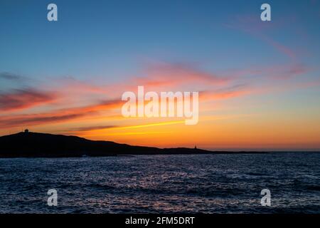 Coucher de soleil sur de petites maisons lumineuses sur l'île de Runde, sur la côte ouest de la Norvège. Banque D'Images