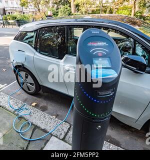 Point de charge de la voiture électrique. Une voiture électrique branchée à un point de recharge public dans les rues de Kensington, dans l'ouest de Londres. Banque D'Images