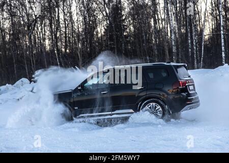 Moscou, Russie - 15 février 2021 : le Kia Mohait 2021 se dresse en 4x4 noir sur la route en forêt d'hiver, déneigeuses. Vue latérale Banque D'Images
