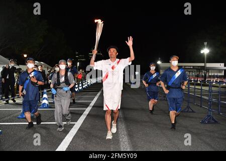 (210506) -- TOKYO, le 6 mai 2021 (Xinhua) -- le sprinter japonais Suetsugu Shingo (C) court avec la torche pendant le relais de la torche olympique de Tokyo dans la préfecture de Kumamoto, au Japon, le 6 mai 2021. (Tokyo 2020/document via Xinhua) Banque D'Images