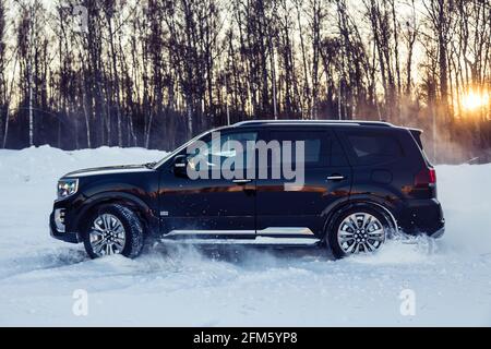 Moscou, Russie - 15 février 2021 : le Kia Mohait 2021 se dresse en 4x4 noir sur la route en forêt d'hiver, déneigeuses. Vue latérale Banque D'Images