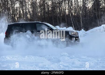 Moscou, Russie - 15 février 2021 : le Kia Mohait 2021 se dresse en 4x4 noir sur la route en forêt d'hiver, déneigeuses. Vue latérale Banque D'Images