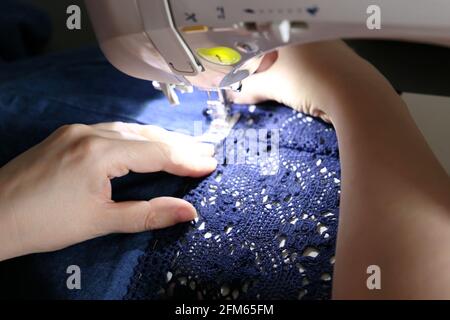 Femme travaillant sur la machine à coudre, les mains des femmes se rapprochent. Robe de couture de couturière, concept de vêtements de mending Banque D'Images