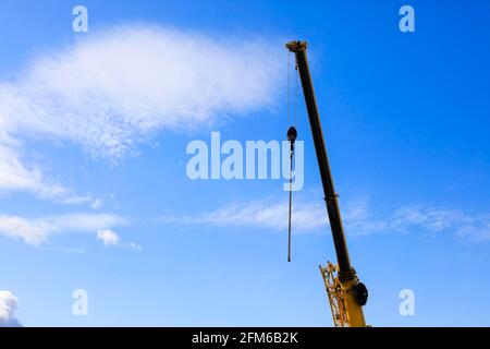 Détail d'une grue en travaux sur un chantier de construction dans un ciel bleu avec des nuages. Banque D'Images