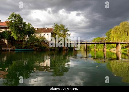 Personnes traversant un pont en bois au-dessus de la rivière Krka en Slovénie, avec la petite ville sourding Kostanjevica Banque D'Images