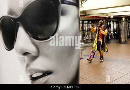 Un artiste de rue afro-américain chantant à l'intérieur de la 34e rue-Herald Square Station de métro avec une affiche noire et blanche en premier plan.Nouveau York City. États-Unis Banque D'Images