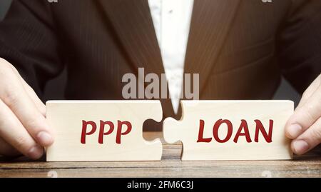 Homme d'affaires met des puzzles avec des mots PPP prêt - Paycheck protection Program. Prêt conçu pour fournir une incitation directe pour les petites entreprises de tenir t Banque D'Images