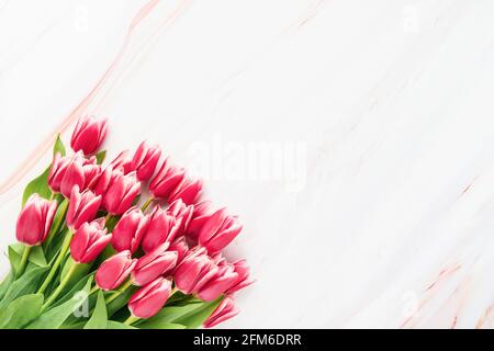 Bouquet de tulipes rose vif sur fond de marbre. Fête des mères, Saint-Valentin, concept de célébration d'anniversaire. Vue de dessus, espace de copie pour le texte Banque D'Images