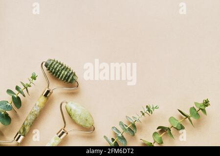 Deux rouleaux à face verte en pierre naturelle de jade et branches d'eucalyptus sur un fond clair. CONCEPT SPA et soin de la peau. Vue de dessus, espace de copie pour le texte Banque D'Images