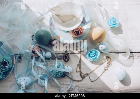 ensemble de thé en porcelaine avec organza bleu décoratif et rubans atlas fleurs et œufs sur une table en bois Banque D'Images