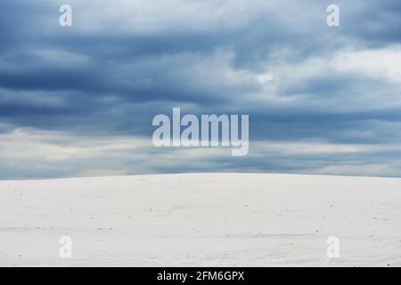 Paysage avec des nuages bleu foncé sur des dunes de sable clair. Banque D'Images