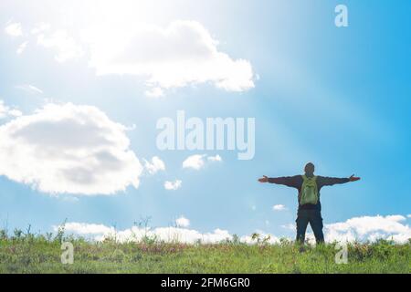 Homme aux mains levées célébrant au sommet de la colline - touriste profitant de la liberté sur la colline - réjouissant au soleil, rayons de lumière, chaleur - fredo Banque D'Images