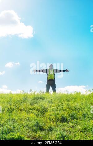 Homme aux mains levées célébrant au sommet de la colline - touriste profitant de la liberté sur la colline - réjouissant au soleil, rayons de lumière, chaleur - fredo Banque D'Images