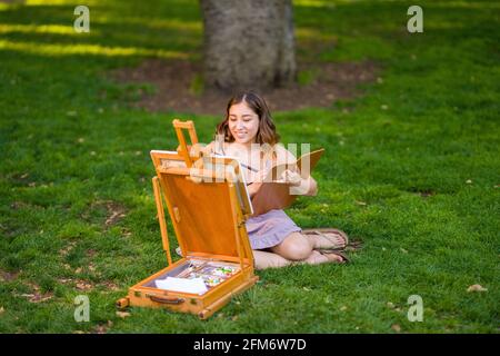 Petite Jeune Femme asiatique étudiant peinture dans le parc utilisation Une armoire Easel Banque D'Images