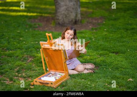 Petite Jeune Femme asiatique étudiant peinture dans le parc utilisation Une armoire Easel Banque D'Images