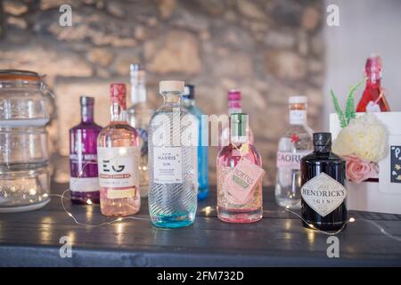 Bouteilles de gin colorées sur une table noire ou bar avec un mur de pierre derrière Banque D'Images