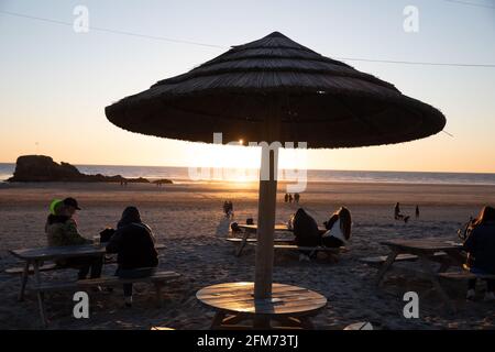 Perranporth, Cornwall, Royaume-Uni, 6 mai 2021 : le soleil pourrait être vu dans toute sa splendeur alors qu'il s'est couché sur Perranporth dans les Cornouailles après une journée ensoleillée qui devrait être la même demain avec un haut de 12C. Le Watering Hole est le seul bar du Royaume-Uni sur la plage avec des parasols de style tropical et est un endroit populaire pour admirer le coucher du soleil de.Credit: Keith Larby/Alay Live News Banque D'Images