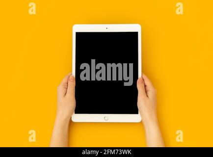 Kharkov, Ukraine - 5 mai 2021: Tablette numérique Apple iPad en main, écran maquette sur fond jaune, vue du dessus Banque D'Images