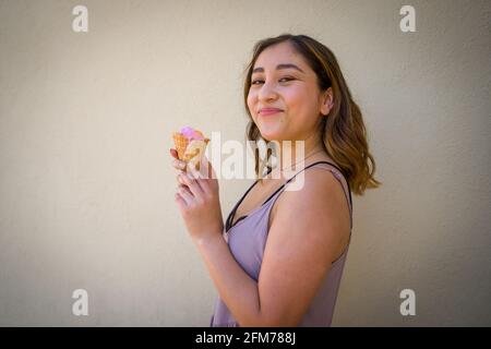 Petite Jeune femme asiatique Eating réaliste Rainbow Sherbet glace Dans un cône de gaufrage en milieu urbain Banque D'Images