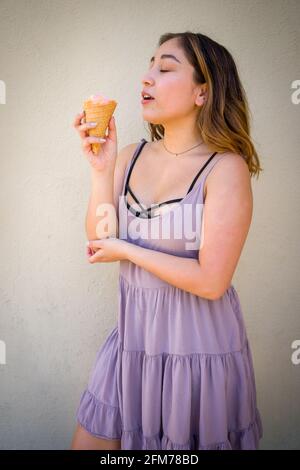 Petite Jeune femme asiatique Eating réaliste Rainbow Sherbet glace Dans un cône de gaufrage en milieu urbain Banque D'Images