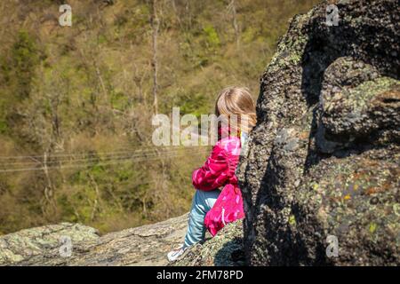 Une fille randonnée pédestre et assis sur le rocher tout en prenant la pause. Adolescente regardant le paysage. Banque D'Images