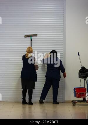 deux nettoyants lavent et désinfectent le mur d'un magasin en quarantaine dans un centre commercial, en prenant soin de la propreté pendant une pandémie de coronavirus Banque D'Images