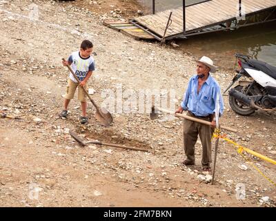 Guatape, Antioquia, Colombie - avril 4 2021 : l'homme latin avec un chapeau blanc à côté de son fils fait un trou dans le sol Banque D'Images