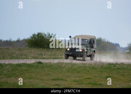 Un Land Rover Defender de l'armée britannique se lance sur une piste poussiéreuse en pierre, lors de manœuvres Banque D'Images