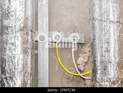 Câbles électriques isolants jaunes et tuyaux métalliques, réparation de toilettes de construction. Banque D'Images