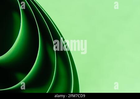 Arrière-plan de macro de couleur abstraite, créé avec des feuilles de papier vertes incurvées. Lignes et formes incurvées et couleurs vives et douces. Banque D'Images