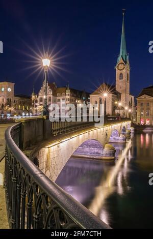 Vue sur le pont et l'eau du lac à l'église Fraumunster à Zurich, Suisse, à l'heure bleue de la nuit Banque D'Images
