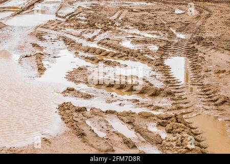 Traces de véhicules de construction dans le sable et les flaques de boue à un chantier de construction Banque D'Images