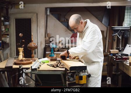 Travailleur du bois dans son atelier faisant des mesures sur une planche de bois Banque D'Images