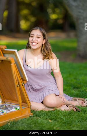 Petite Jeune Femme asiatique étudiant peinture dans le parc utilisation Une armoire Easel Banque D'Images