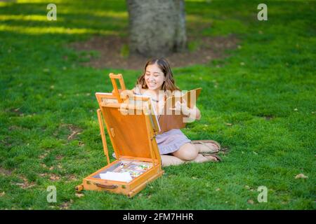 Petite Jeune Femme asiatique étudiant peinture dans le parc utilisation Une armoire Easel Banque D'Images