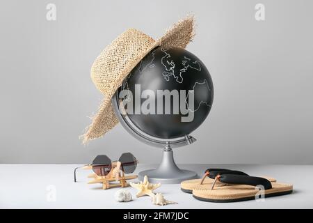 Globe avec accessoires de plage sur fond gris Banque D'Images