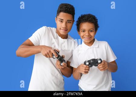Garçons afro-américains jouant au jeu vidéo sur fond de couleur Banque D'Images