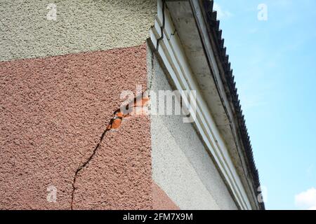 Une grave fissure de stuc sur le coin de la maison près du toit. Réparer une fissure de stuc sur le mur de la maison. Banque D'Images