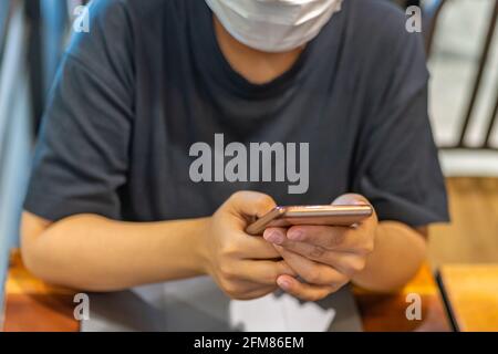 Femme portant un masque médical et utilisant un smartphone Banque D'Images