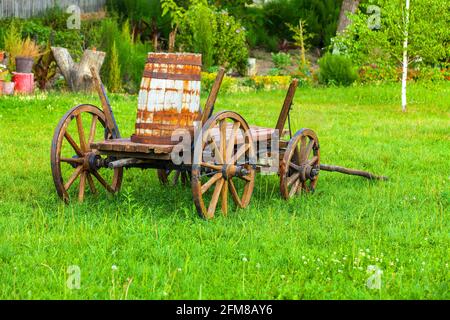 Ancien chariot en bois avec un fût sur l'herbe verte Banque D'Images