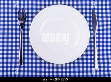 Empy plate et avec une fourchette de couteau sur la nappe dans une cage. Vue de dessus avec espace de copie Banque D'Images