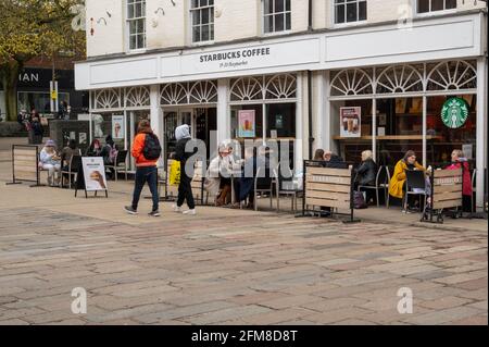 Une vue sur le café Starbucks au centre de Norwich avec des personnes assises à l'extérieur se détendre et boire après la réduction des directives COVID. Banque D'Images