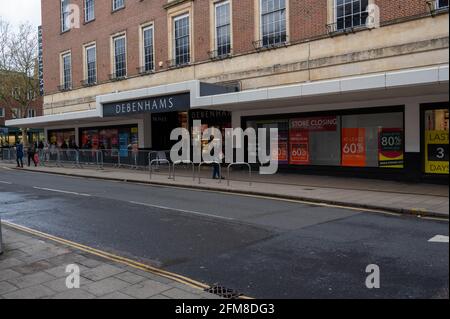 Centre-ville de Norwich, rue hippique rampante, façade Debenhams avec tous les rabais et fermer les affiches dans les fenêtres et les barrières métalliques pour les acheteurs Banque D'Images