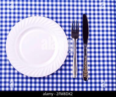 Empy plate et avec une fourchette de couteau sur la nappe dans une cage. Vue de dessus avec espace de copie Banque D'Images