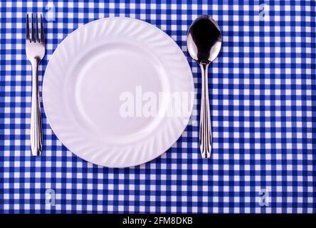 Empy plate et avec une cuillère fourchette sur la nappe dans une cage. Vue de dessus avec espace de copie Banque D'Images