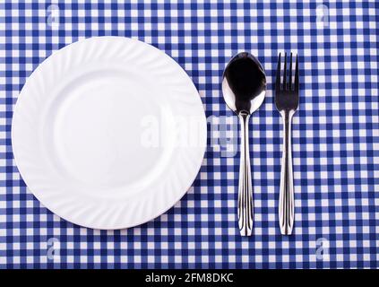 Empy plate et avec une cuillère fourchette sur la nappe dans une cage. Vue de dessus avec espace de copie Banque D'Images