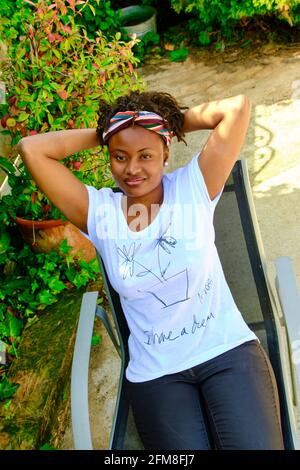 Jeune femme africaine avec un style de cheveux frais et un t-shirt posant à l'extérieur. Banque D'Images