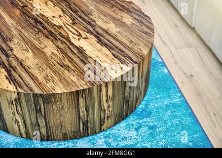 Élégante table à café ronde texturée contemporaine en contreplaqué et Placage naturel Ofram noir sur moquette bleue dans la chambre Banque D'Images