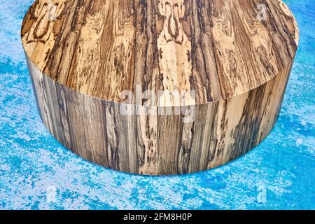 Élégante table à café ronde texturée contemporaine en contreplaqué et Placage naturel Ofram noir sur moquette bleue dans la chambre Banque D'Images